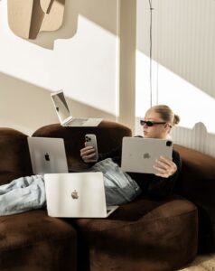 Mujer trabajando con varios ordenadores para gestionar la captación de clientes en su negocio de UGC.