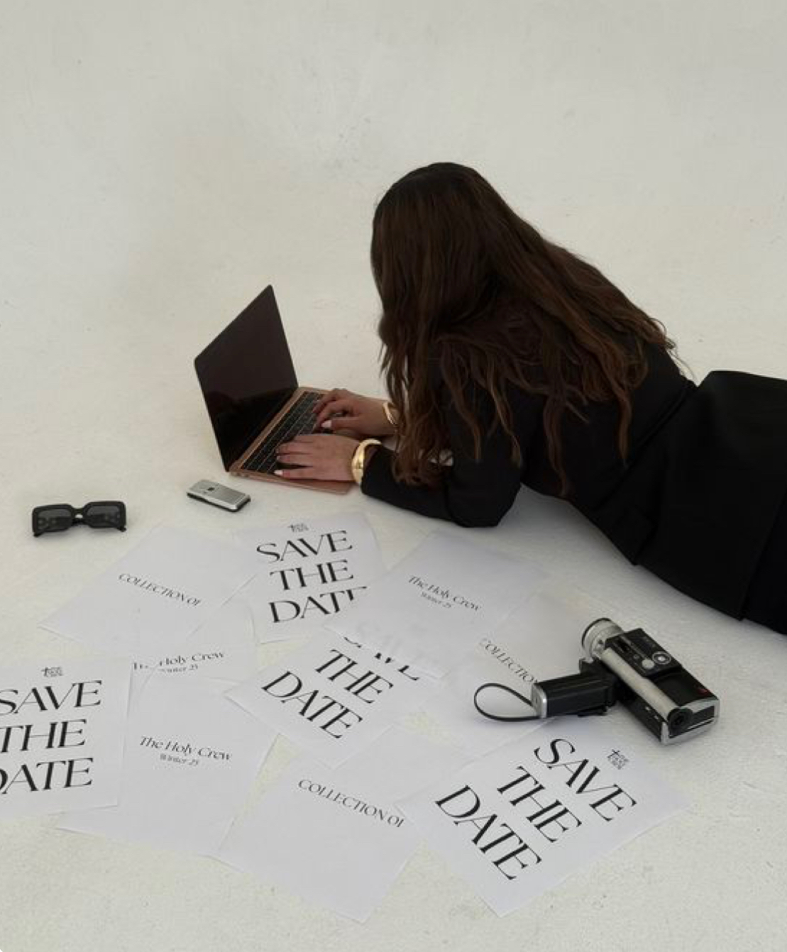 Chica en el suelo creando contenido UGC con su portátil y carteles publicitarios.